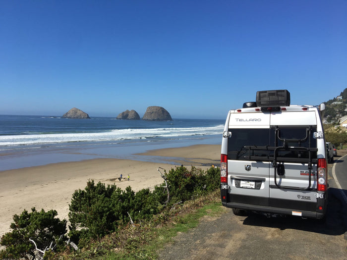 RV rental overlooks a stunning beach with sea stacks & crashing waves, ideal for coastal travel.