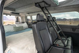 Inside an RV rental camper van: comfortable bed, rear seats, and ladder to an upper bunk, with scenic views.