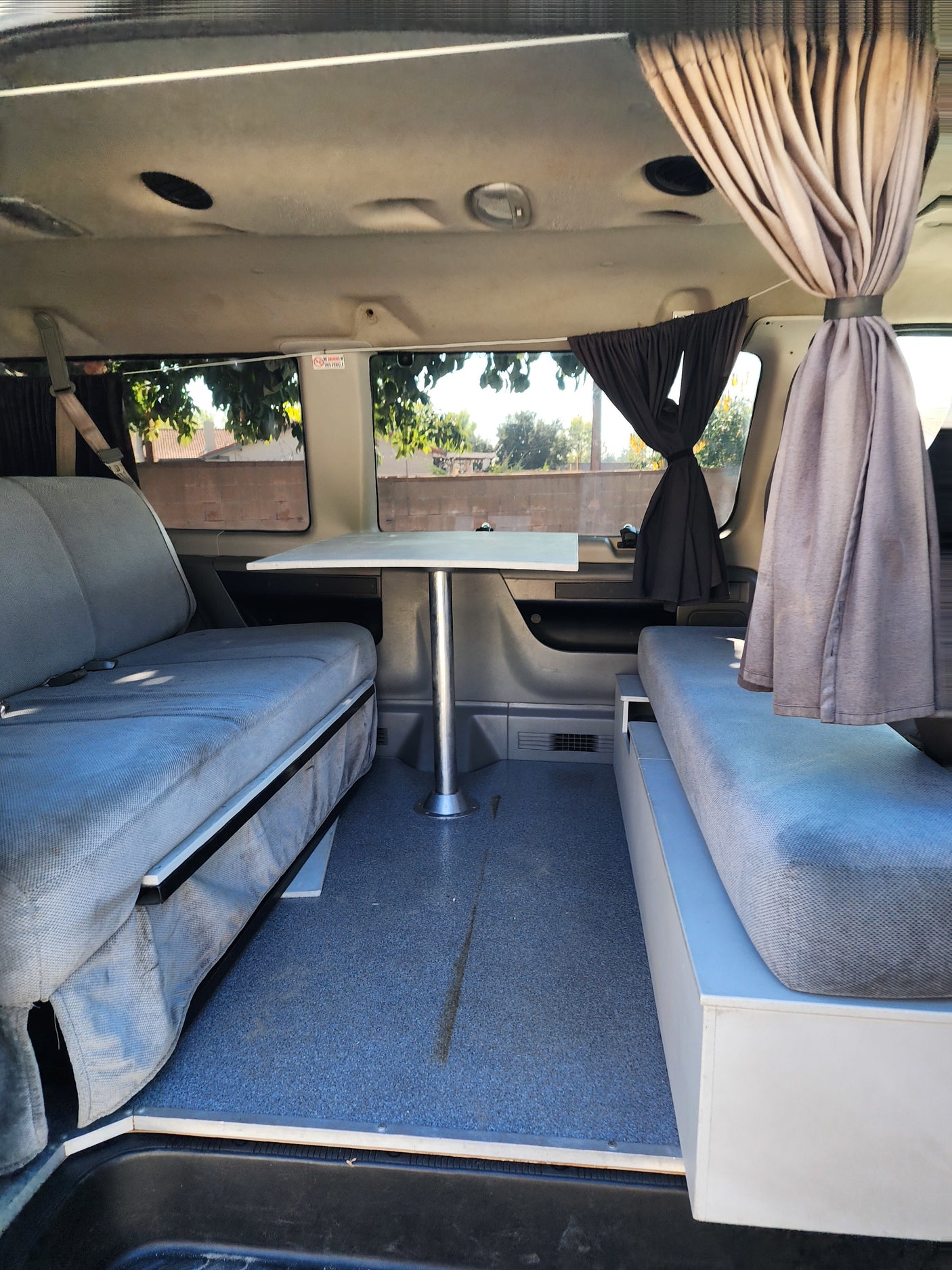 Cozy rv rental interior with facing benches, central table, and curtains, ideal for compact travel and camping.