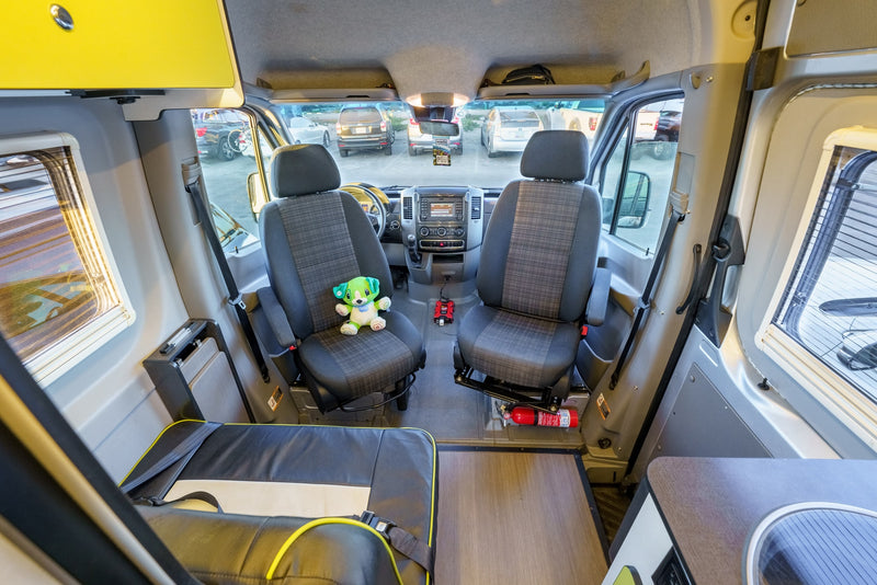 This rv rental camper van interior features a well-equipped dashboard, comfortable front seats, and overhead storage. — photo 13