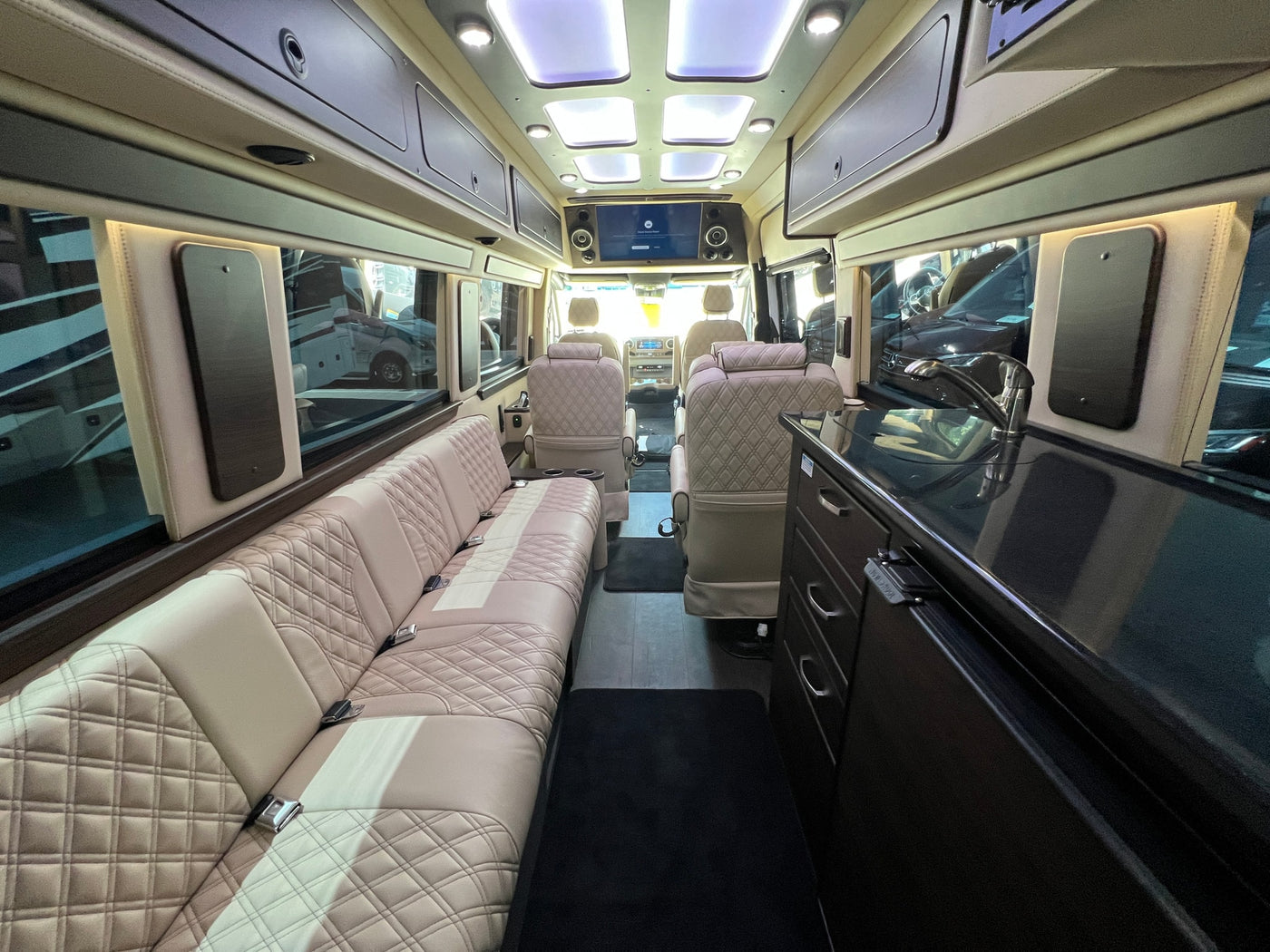 Explore this luxurious RV rental interior featuring diamond-stitched seating, ample storage, and modern amenities for travel. — photo 11