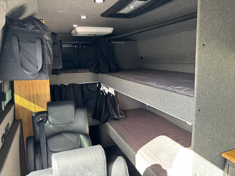 Inside this RV rental: modern camper van interior featuring bunk beds, swivel seats, overhead AC, and storage. — photo 5