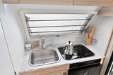 Compact RV rental kitchen featuring a sink, stovetop with a kettle, and marble-look counters for your adventures.