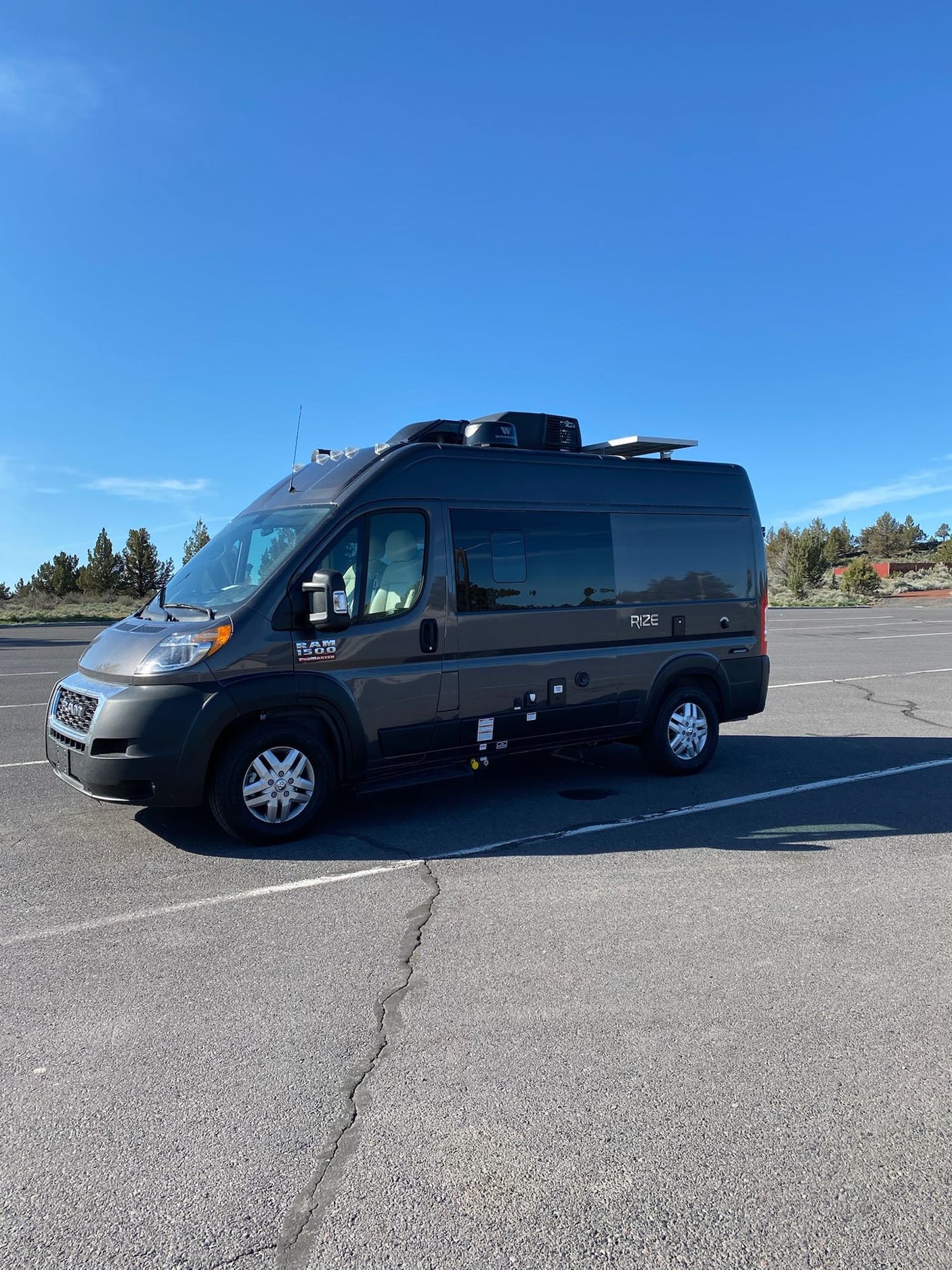 Dark gray Thor Rize camper van, an ideal rv rental, parked in a bright outdoor lot.