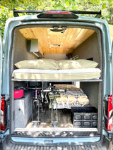 This RV rental's rear interior features an upper bed, bikes secured below, and a lower bed with storage crate.