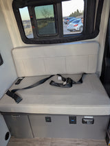 Comfortable RV rental interior: bench seat with seatbelts, power outlets & scenic window views for your journey.