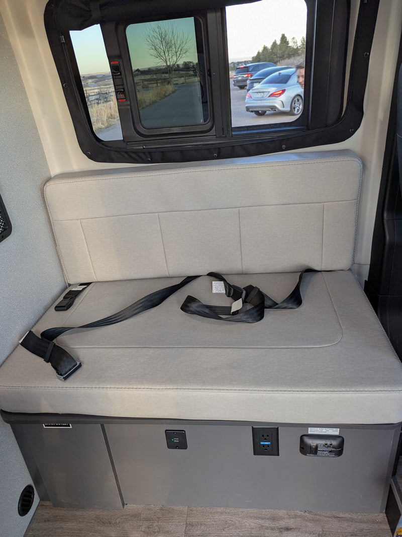 Comfortable RV rental interior: bench seat with seatbelts, power outlets & scenic window views for your journey. — photo 5