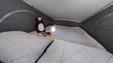 Cozy quilted bed inside an RV rental, featuring a plush bear and glowing lantern for comfortable camping nights.