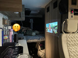 Relaxing inside an RV rental. A movie is projected on the wall, illuminating the interior while someone rests on the bed.