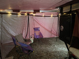 Spacious interior of an RV rental annex with camping chairs, string lights, and a gravel floor for outdoor comfort.