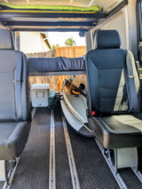 This RV rental van interior features flexible seating, an overhead bunk bed, and ample storage for adventure gear & paddleboards.