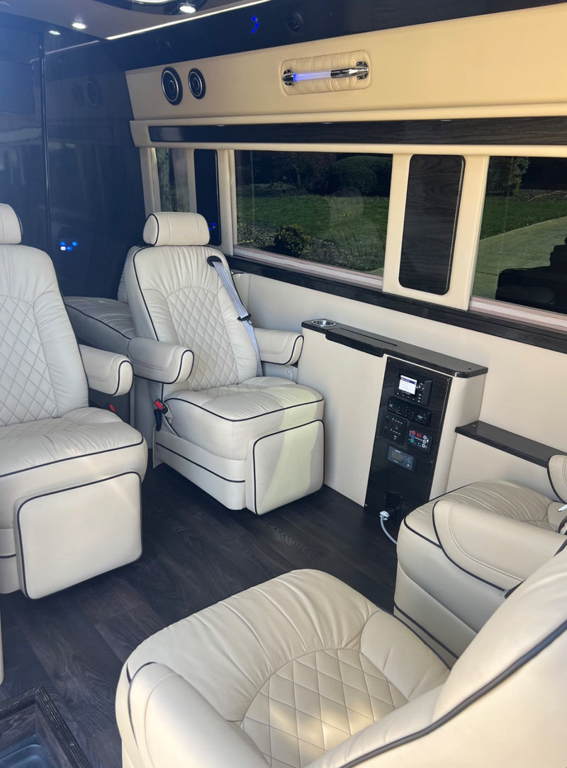 Luxury RV rental interior with cream leather captain's chairs, wood flooring, and modern control panel. — photo 5