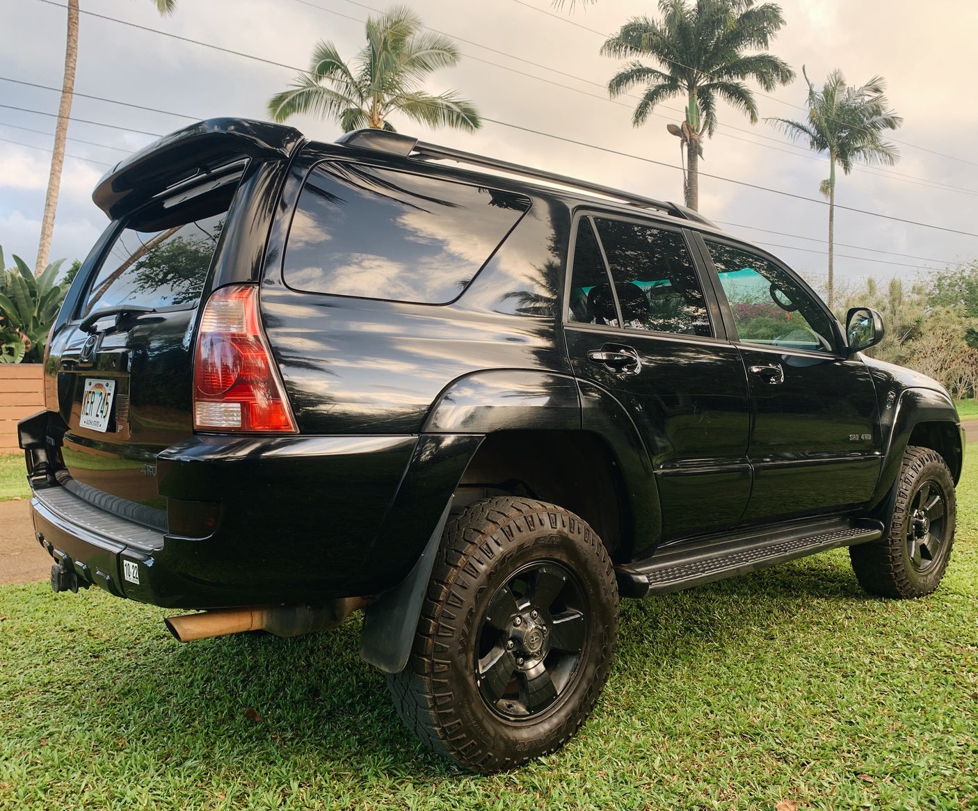 A black SUV, ideal for exploring Hawaii's landscapes, parked on grass. A great travel option, perhaps alongside an rv rental.
