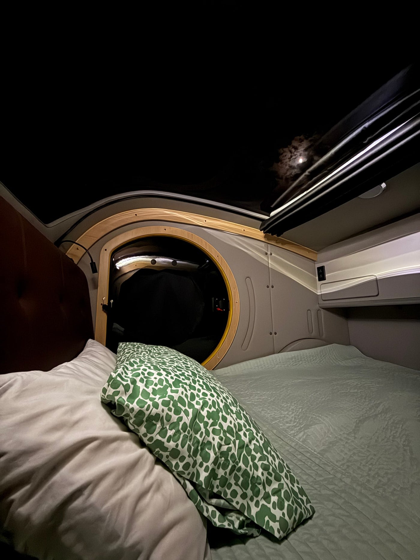 Cozy RV rental interior at night. The full moon shines through the roof opening, illuminating a comfortable bed with a green pillow. — photo 14