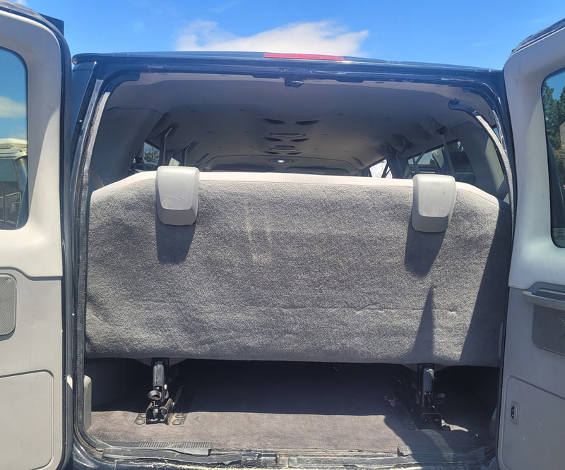  indicating an RV rental facility.|Inside an RV rental: multiple rows of gray fabric seats with visible seatbelts and buckle mechanisms. Other RVs are outside.|Spacious RV rental interior: rear view with open doors — photo 6
