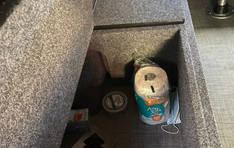 RV rental storage: Paper towels, vegan tzatziki dip, and a face mask are neatly organized in a carpeted compartment.