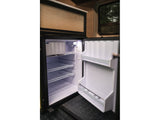 RV rental compact fridge, door open. Interior shows wire shelves, door storage, and small top freezer compartment. Ready for your adventure.