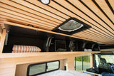 RV rental interior: overhead storage, fan, and controls set against a warm, slatted wooden ceiling. Bedding ready for travelers.