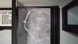 Inside an RV rental: a modern shower with faux grey tiles and an adjacent air conditioner.