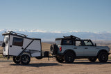 Explore with an RV rental! This Ford Bronco tows a TigerMoth overland trailer with mountain views, perfect for adventure.