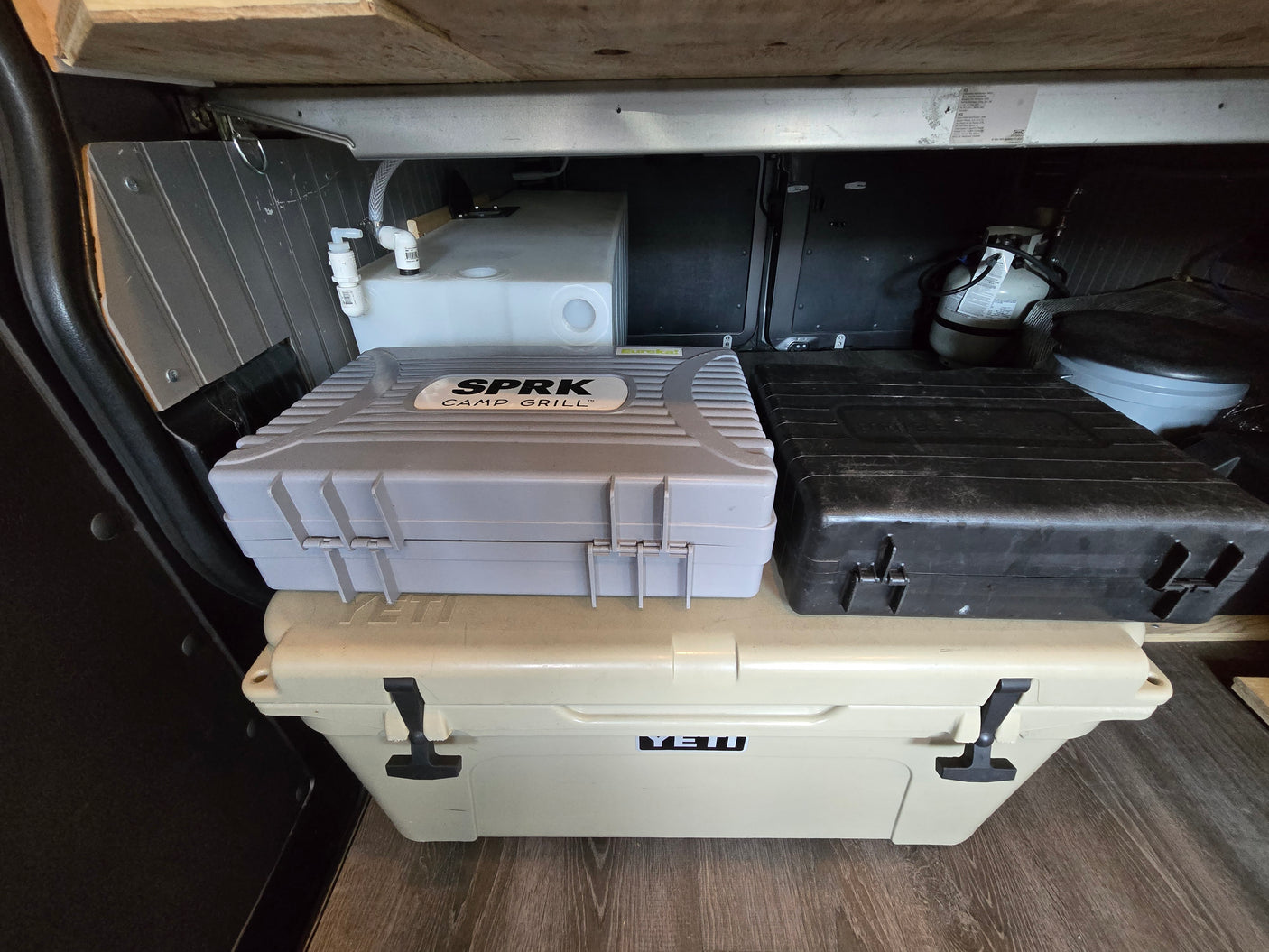 RV rental camp setup: Yeti cooler, SPRK grill, water tank, propane, & portable toilet for convenience.