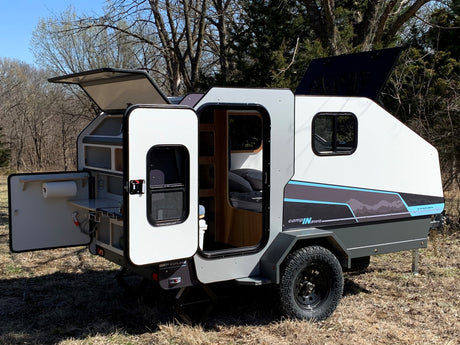 A sleek, compact rv rental camper with an outdoor kitchen & interior bed, ideal for off-grid adventures in nature.