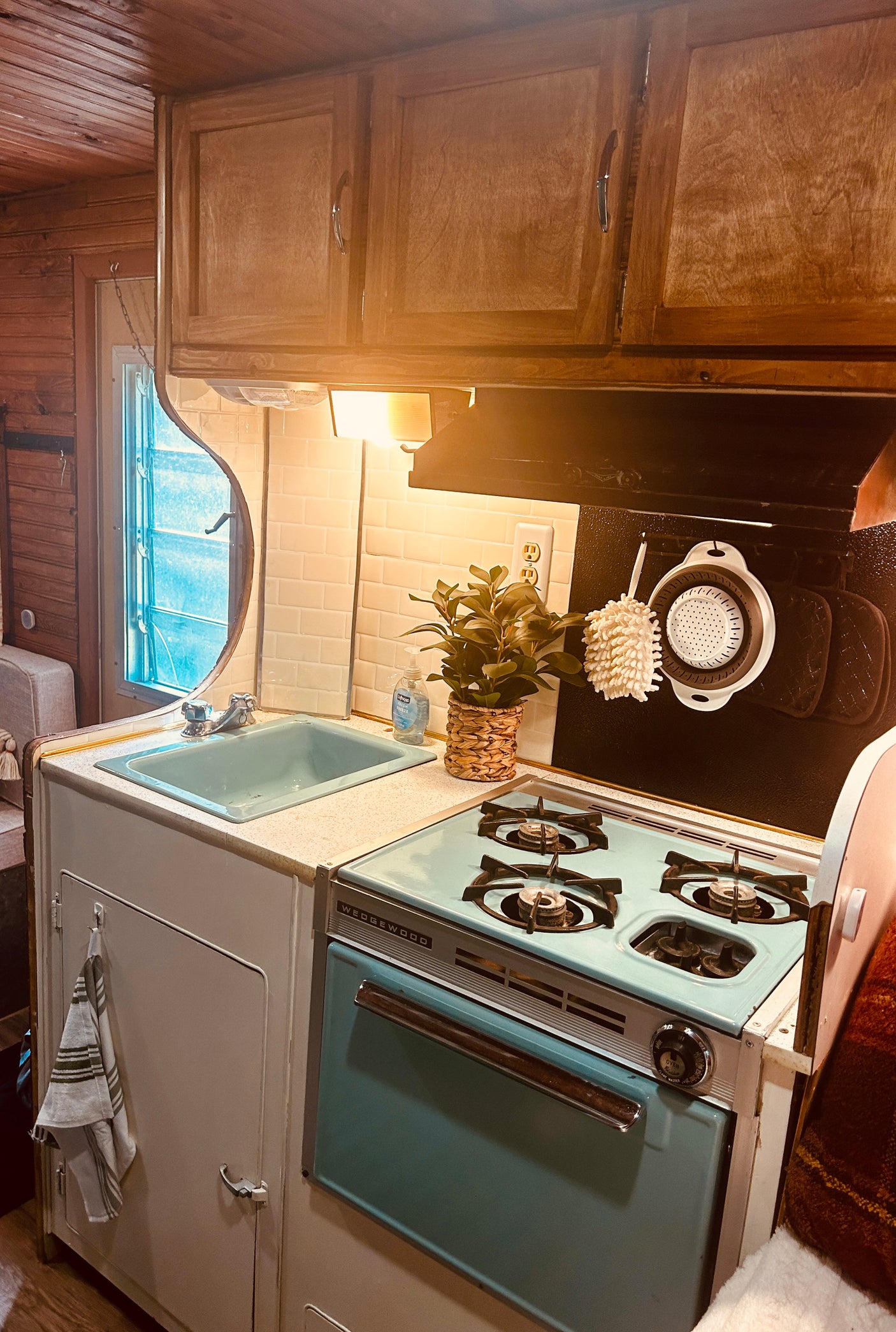 Inside an **rv rental**: a compact kitchen with a vintage light blue Wedgewood stove, matching sink, subway tile, and wood cabinets.