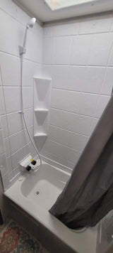 This RV rental offers a clean, compact white shower stall, complete with built-in shelves and a handheld showerhead.