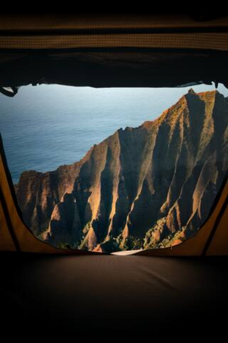 An epic RV rental view: rugged mountains meet the ocean, seen from inside a tent or vehicle opening. Perfect for scenic travel.
