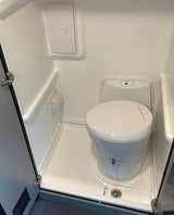 This RV rental offers a compact wet bath with a toilet, shower area (drain visible), and overhead storage.