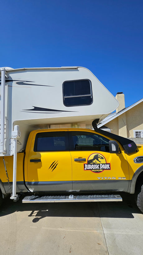 Unique yellow Jurassic Park pickup truck with a white truck camper, a fantastic option for an unforgettable rv rental.