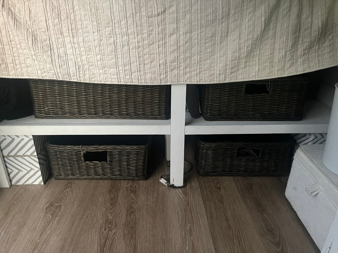Maximizing space in an RV rental: under-bed storage with dark woven baskets on white shelves. — photo 11