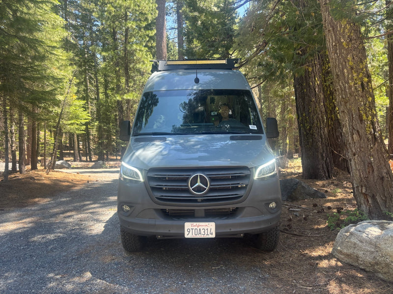  ready for travel.|This gray Mercedes Sprinter rv rental is parked on a forest road. A smiling driver and dog enjoy the sunny outdoor adventure.|Spacious RV rental camper van interior with open doors — photo 4