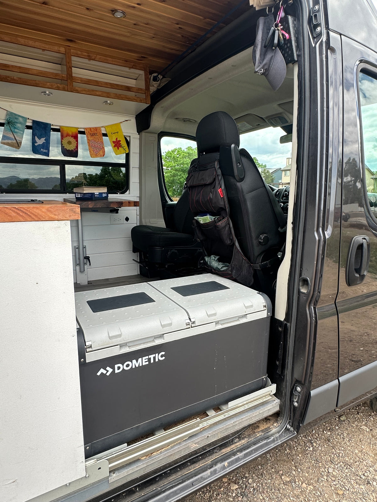 Inside an RV rental: Dometic cooler on a slide-out, wood ceiling, custom counter, and decorative flags. — photo 14