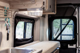 Inside this inviting rv rental, a camper van interior with comfortable seating, a small kitchen, and large windows with nature views.