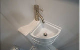 A sleek, space-saving corner sink with a modern faucet, perfect for an RV rental's compact bathroom.