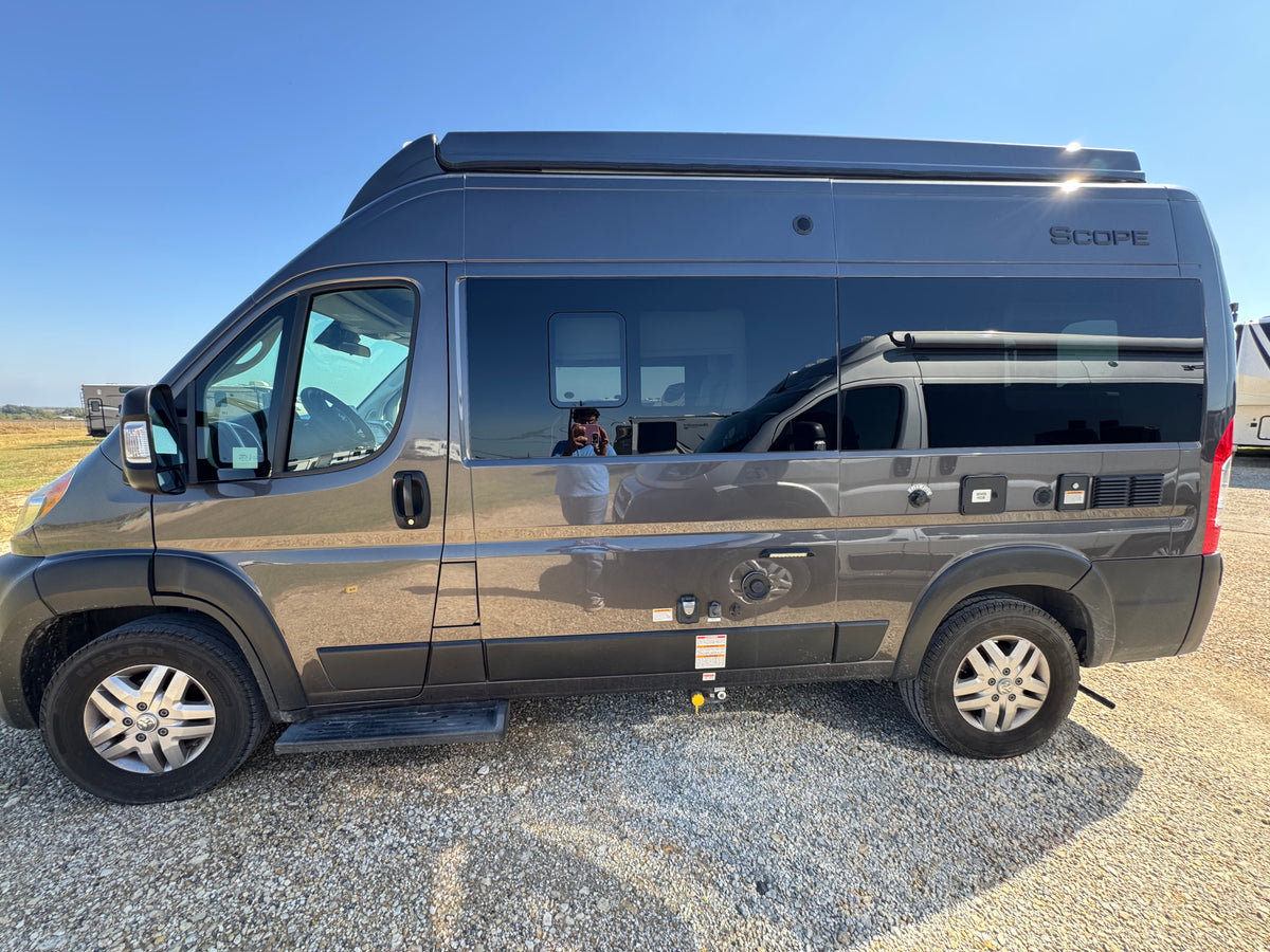 This gray Scope camper van, equipped with exterior hookups, is ready for RV rental on a sunny day.