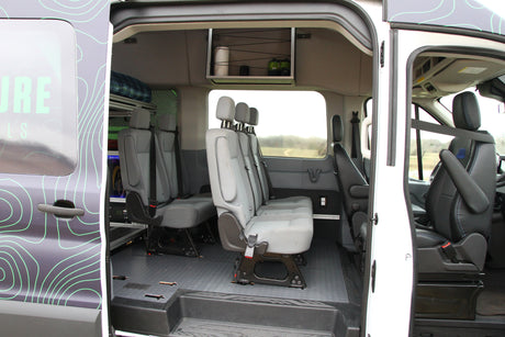 Spacious RV rental interior with multiple passenger seats, overhead storage, and durable flooring for comfortable group travel.