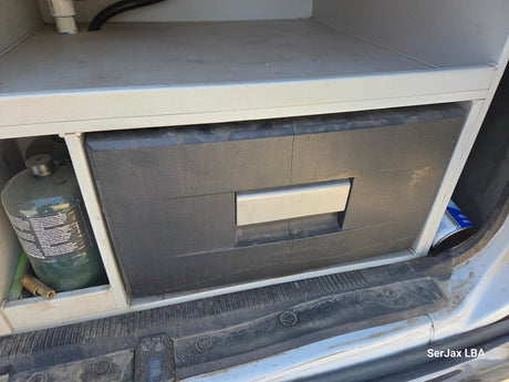 RV rental: A portable fridge, a green propane tank, and other supplies are neatly stored in a van's custom interior.