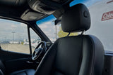Mercedes-Benz RV rental interior: black seats, steering wheel, dashboard. Outside view of lot. Adventure awaits.