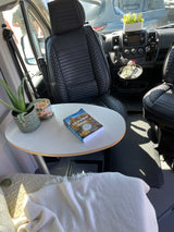 Cozy RV rental interior with a table, hiking book, and plants, ready for a comfortable and adventurous trip.