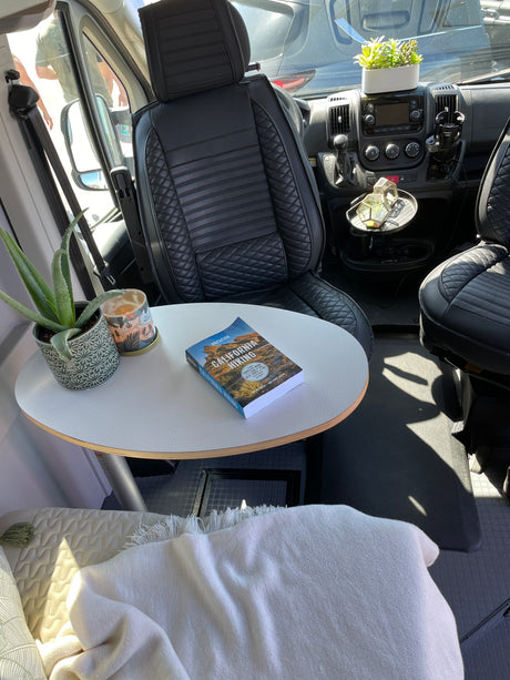 Cozy RV rental interior with a table, hiking book, and plants, ready for a comfortable and adventurous trip.