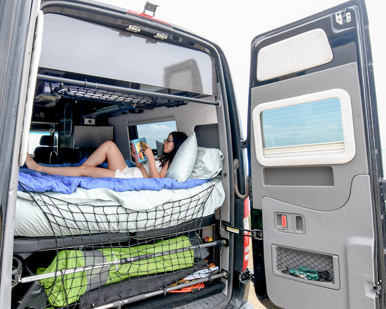  revealing cozy bed & storage.|Spacious RV rental interior featuring black leather seating — photo 3