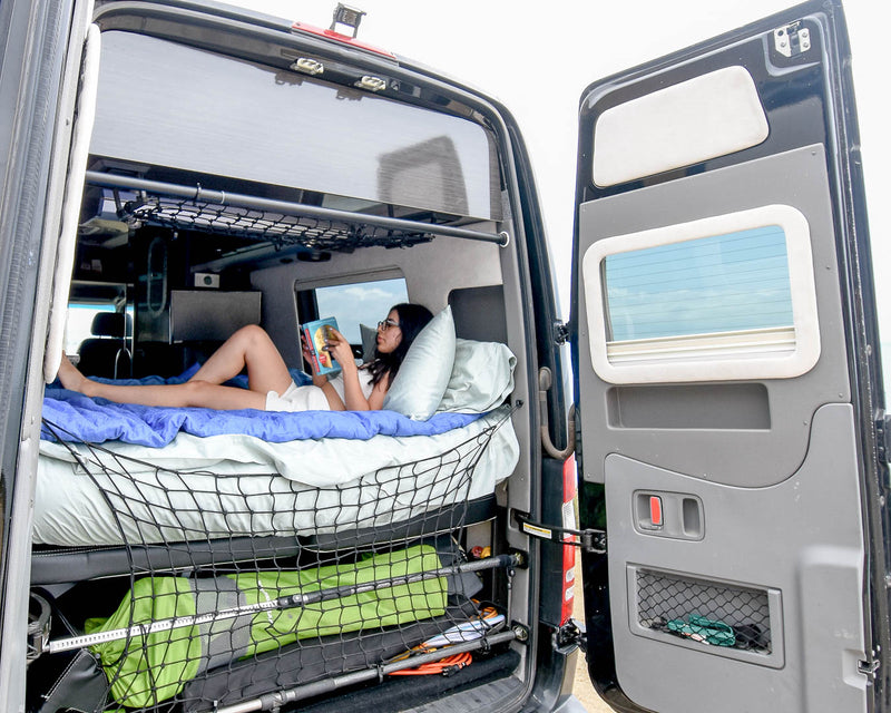  revealing cozy bed & storage.|Spacious RV rental interior featuring black leather seating — photo 3
