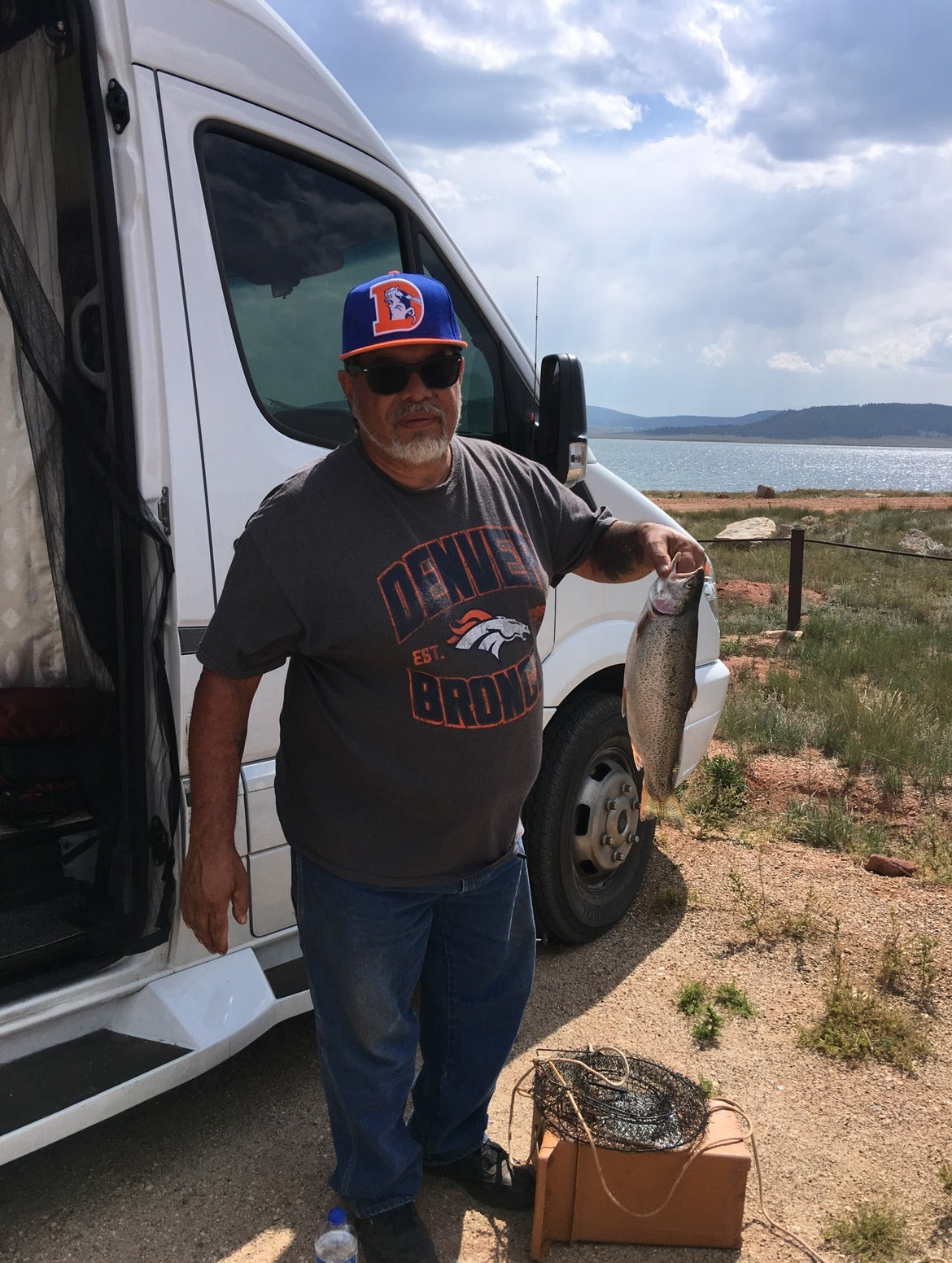Man with his fishing catch next to an RV rental, by a lake under cloudy skies. — photo 6