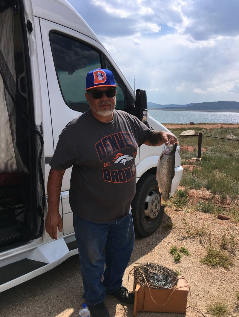 Man with his fishing catch next to an RV rental, by a lake under cloudy skies. — photo 6