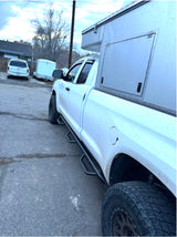 Dirty white pickup truck featuring a custom, rugged camper body with off-road tires. Ideal for adventurous RV rental trips.