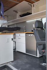 Compact rv rental interior with kitchen, bed, overhead storage, and fridge. Ideal for mobile living.