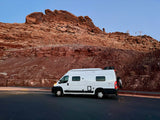 Experience travel freedom with an RV rental: White camper van beside stunning red rock mountains and a cable car.