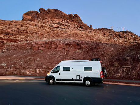 Experience travel freedom with an RV rental: White camper van beside stunning red rock mountains and a cable car.
